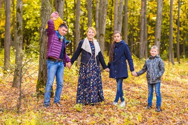 Family, childhood, season and people concept - happy family playing with autumn leaves in park — Stock Photo, Image