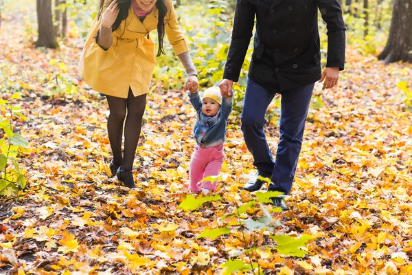 Niña pequeña cogida de la mano con su madre y su padre afuera en un día de otoño — Foto de Stock