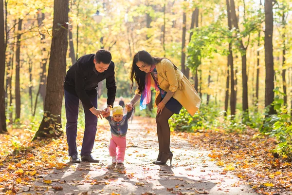 Счастливая молодая семья с дочкой проводят время на свежем воздухе в осеннем парке — стоковое фото