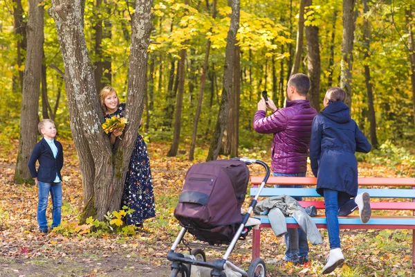 Familie, jeugd, seizoen, technologie en mensen concept - fotograferen in herfst park en gelukkige familie — Stockfoto