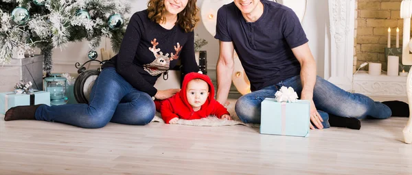 Gelukkige familie bedrijf van de giften van Kerstmis in de buurt van de kerstboom. Baby, moeder en vader plezier thuis — Stockfoto