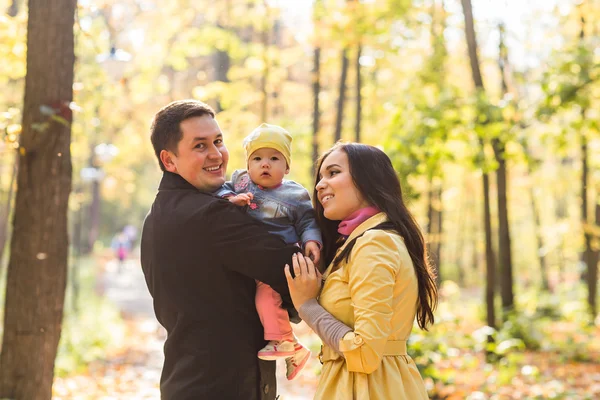 Láska, rodičovství, Rodina, sezóna a lidé koncept - usmívající se pár s dítětem na podzim park — Stock fotografie