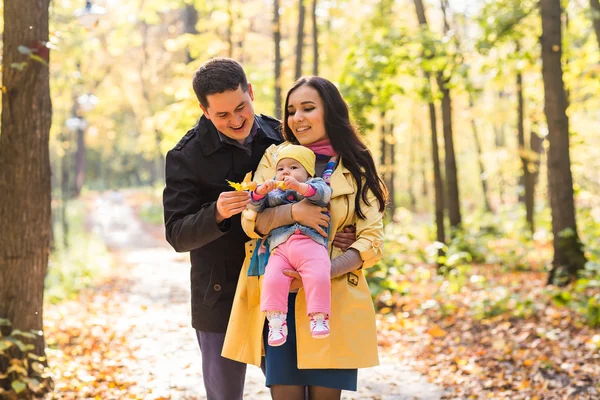 Familia joven y feliz con su hija pasando tiempo al aire libre en el parque de otoño — Foto de Stock