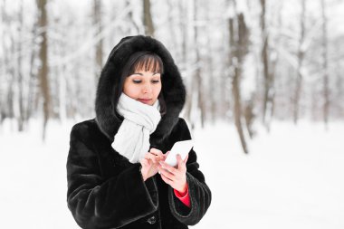 Smartphone ve kış manzara kar taneleri arka planda olan kadın