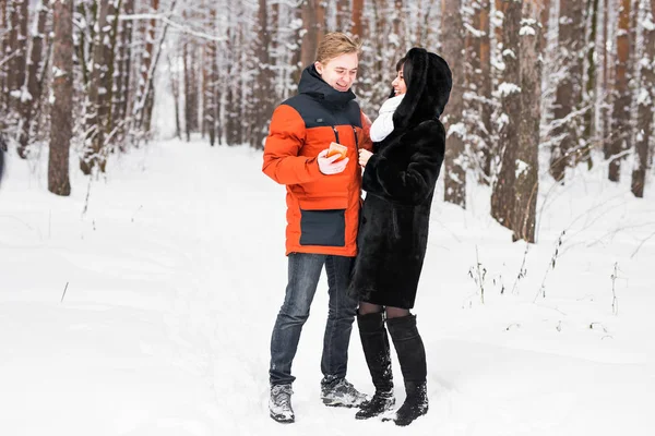 冬の屋外でスマート フォンをコンサルティングする幸せなカップル — ストック写真