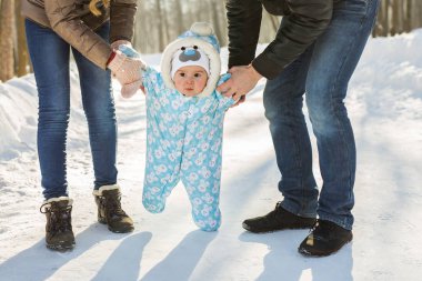 Biraz yürümeyi öğrenme bebeğim. Annesi ve babası ile kış parkta yürümeye başlayan çocuk