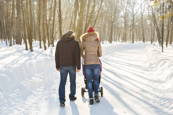 Far och mor med barnvagn i vinter skog — Stockfoto