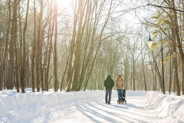 Père et mère avec poussette dans la forêt d'hiver — Photo