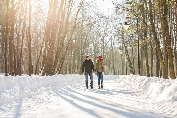 Casal feliz caminhando por uma floresta nevada no inverno — Fotografia de Stock