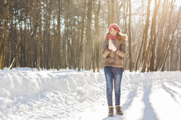 Ομορφιά κορίτσι φυσάει χιόνι παγωμένο χειμώνα πάρκο. Σε εξωτερικούς χώρους. Που φέρουν νιφάδες χιονιού. — Φωτογραφία Αρχείου