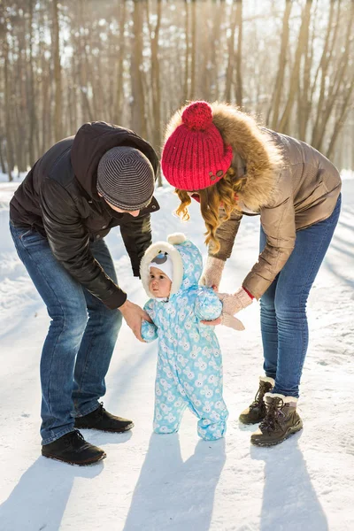 First steps. Little baby learning to walk. Mother and father with toddler boy at the winter park — Stock Photo, Image