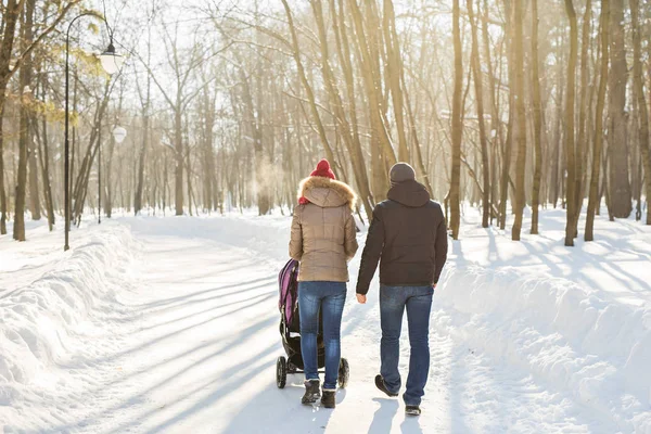 Father and mother with baby carriage in winter forest — Stock Photo, Image