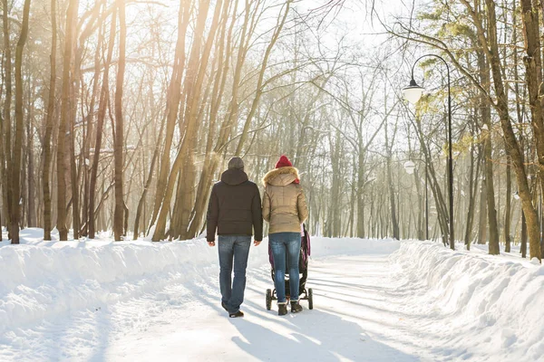 Far och mor med barnvagn i vinter skog — Stockfoto