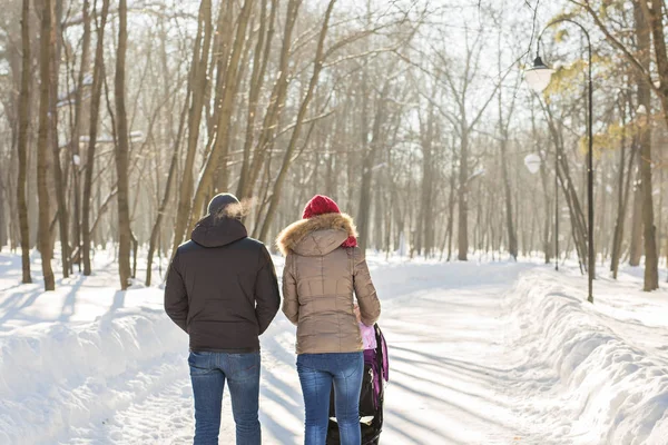 Far och mor med barnvagn i vinter skog — Stockfoto