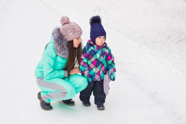 karlı kış ormandaki yürüyüşte kız bebek tutan mutlu anne