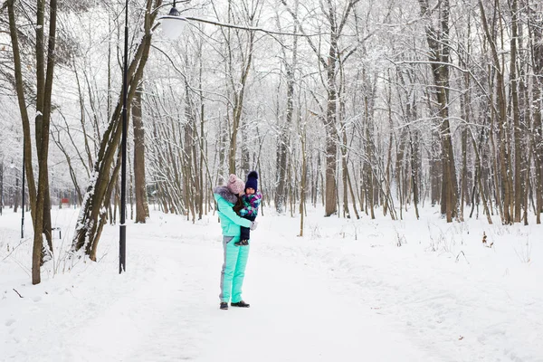 Mãe feliz segurando bebê menina no passeio no inverno floresta nevada — Fotografia de Stock