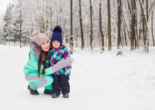 Mãe e pequena menina caminhando na floresta de inverno e se divertindo com a neve. Família desfrutando de inverno. Conceito de Natal e estilo de vida . — Fotografia de Stock