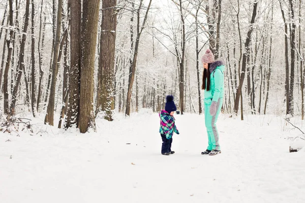 Família feliz mãe e criança bebê filha em um passeio de inverno na floresta — Fotografia de Stock