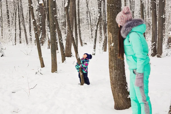 Mãe e pequena menina caminhando na floresta de inverno e se divertindo com a neve. Família desfrutando de inverno. Conceito de Natal e estilo de vida . — Fotografia de Stock