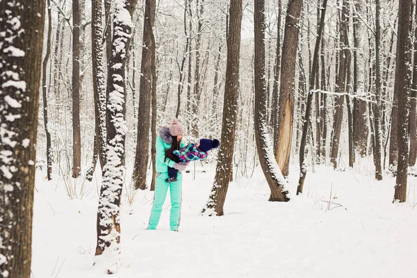 Mãe e pequena menina caminhando na floresta de inverno e se divertindo com a neve. Família desfrutando de inverno. Conceito de Natal e estilo de vida . — Fotografia de Stock