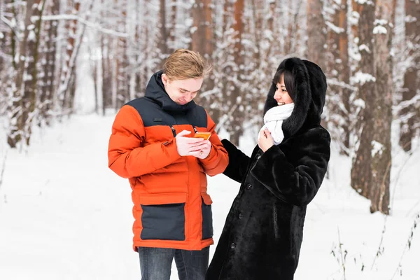 冬の自然でスマート フォンと友達のカップル — ストック写真