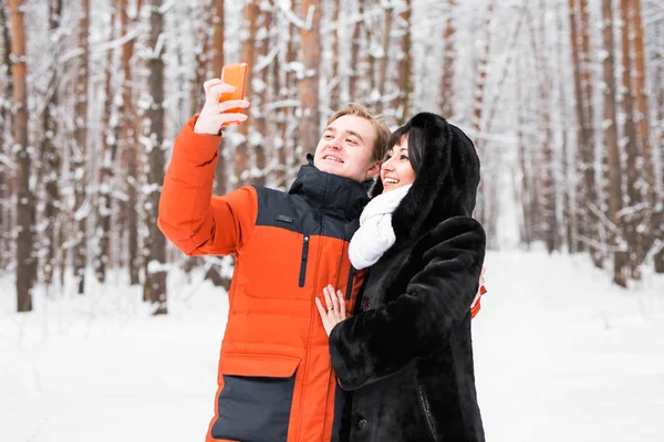 คู่รักที่มีความสุขในฤดูหนาวถ่ายรูปตัวเองด้วยสมาร์ทโฟน — ภาพถ่ายสต็อก