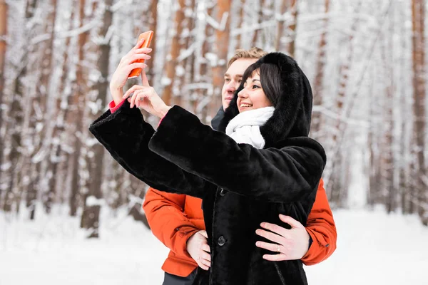 Casal feliz no inverno tirando fotos de si mesmos com smartphone — Fotografia de Stock