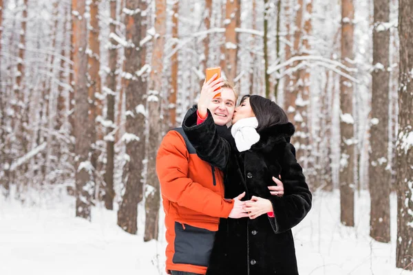 冬のスマート フォンで自分の写真を撮る幸せなカップル — ストック写真