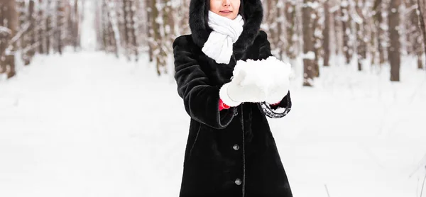 Close-up of woman holding natural soft white snow in her hands to make a snowball, smiling during a cold winter day in the forest, outdoors. — Stock Photo, Image