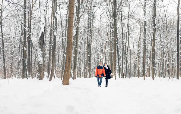 Счастливая молодая пара в зимнем парке веселится. Семья на открытом воздухе — стоковое фото