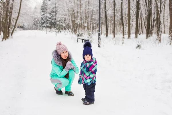 Mãe feliz e bebê menina no passeio no inverno floresta nevada — Fotografia de Stock