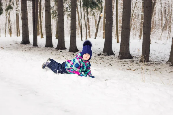 Сміється дівчинка лежить на снігу — стокове фото