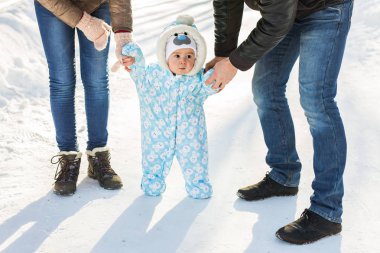 Sıcak snowsuit bir anne ile kış parkta yürüyüş bebek çocuk. İlk kış ve ilk yürümeye başlayan çocuk adımları kar üzerinde.