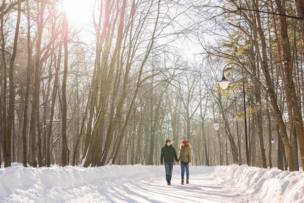 Jeune couple amoureux marchant dans la forêt enneigée — Photo