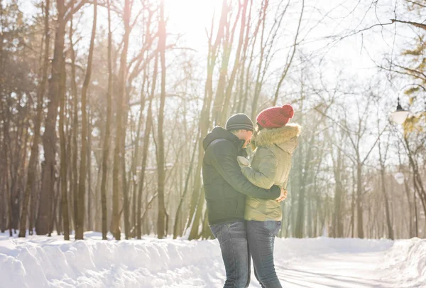 Jovem casal abraçando e beijando no parque no inverno . — Fotografia de Stock