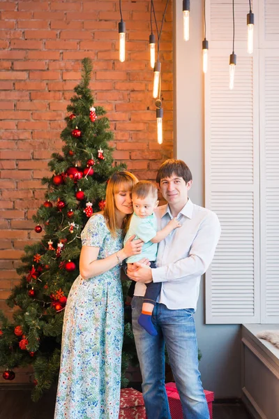 Família de Natal com criança. Pais sorridentes felizes e crianças em casa celebrando o ano novo. Árvore de Natal . — Fotografia de Stock