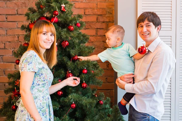 Familia sonriente decorando un árbol de Navidad en la sala de estar —  Fotos de Stock