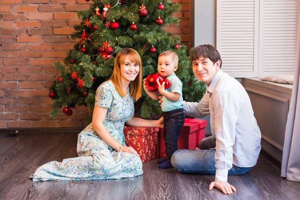 Família de Natal com criança. Pais sorridentes felizes e crianças em casa celebrando o ano novo. Árvore de Natal . — Fotografia de Stock