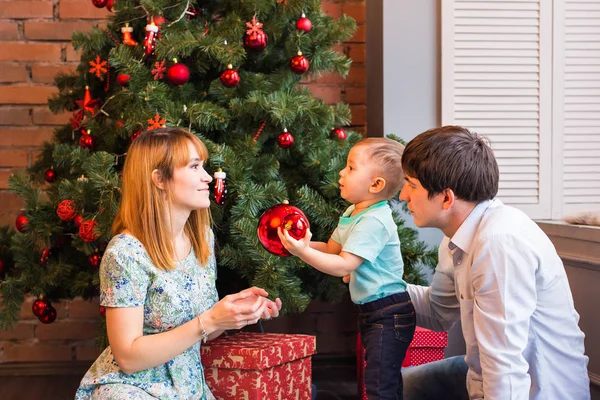 Święta Rodzina z dzieckiem. Szczęśliwy uśmiechający się rodzice i dzieci w domu z okazji nowego roku. Choinka. — Zdjęcie stockowe