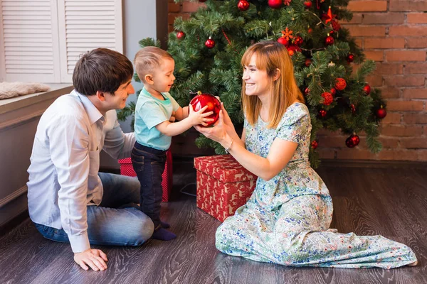 Familia de Navidad con niño. Felices padres e hijos sonrientes en casa celebrando el Año Nuevo. Árbol de Navidad . — Foto de Stock