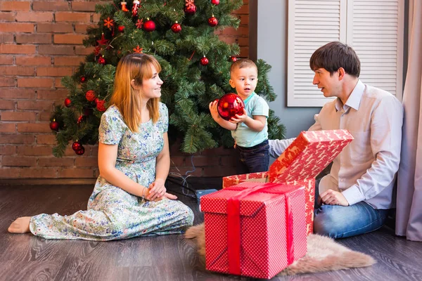 Familia de Navidad con niño. Felices padres e hijos sonrientes en casa celebrando el Año Nuevo. Árbol de Navidad . — Foto de Stock