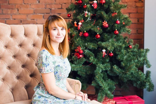 Retrato de una joven feliz relajándose cerca del árbol de Navidad —  Fotos de Stock