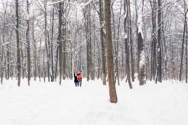 Mutlu çift kışın karlı bir ormanda yürüyor.