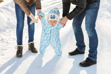 Sıcak snowsuit bir anne ile kış parkta yürüyüş bebek çocuk. İlk kış ve ilk yürümeye başlayan çocuk adımları kar üzerinde.