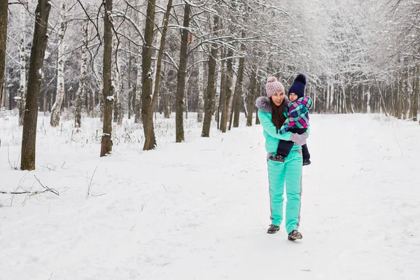 Mãe feliz e bebê menina no passeio no inverno floresta nevada — Fotografia de Stock