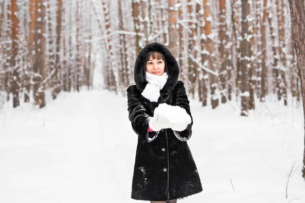 Sonriente mujer sosteniendo nieve en mitones — Foto de Stock