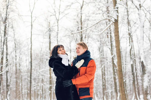 Jovem casal apaixonado andando na floresta nevada — Fotografia de Stock