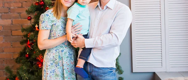 Família de Natal com criança. Pais sorridentes felizes e crianças em casa celebrando o ano novo. Árvore de Natal . — Fotografia de Stock