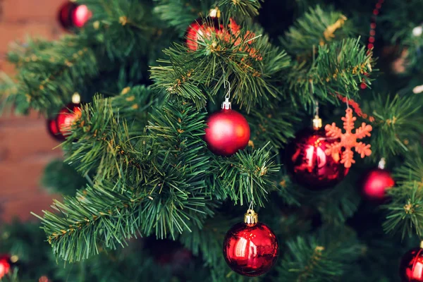 Closeup de bugigangas vermelhas penduradas em uma árvore de Natal decorada . — Fotografia de Stock
