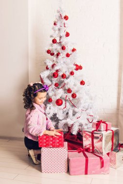 çocuk beyaz Noel ağacının yanında hediye kutusu